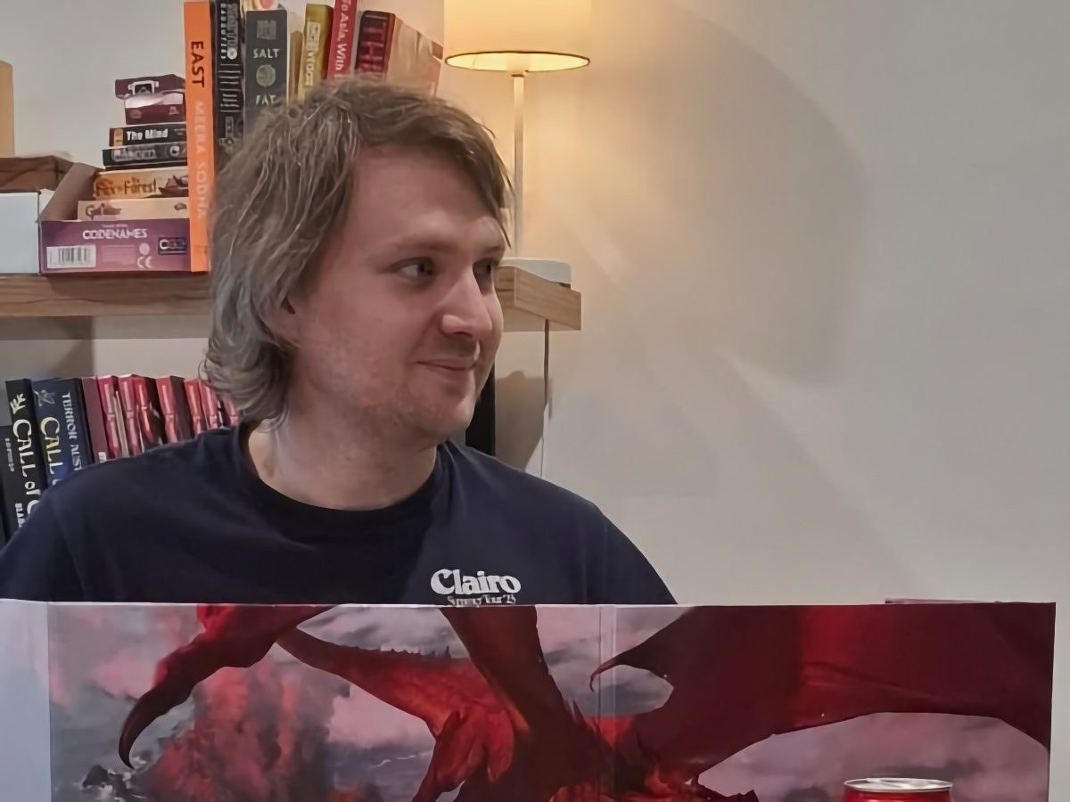 A photo of Max behind a DM screen, slightly smiling and eyeing an off-screen player with admiration and suspicion